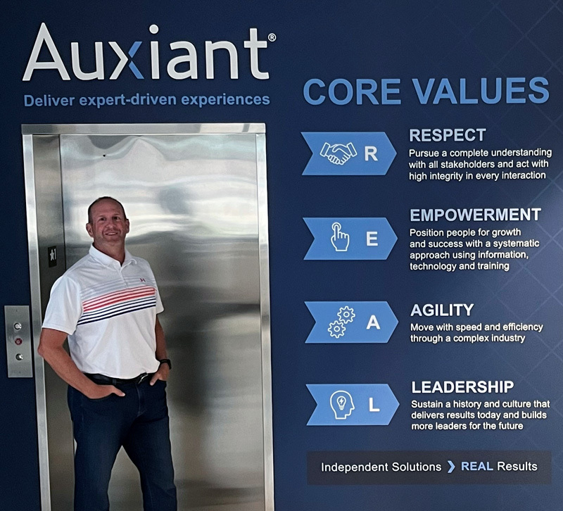 Employee standing by elevator with core values display.